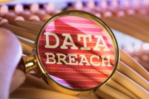 magnifying glass held over files enlarging the words 'data breach'
