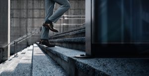 A man in a suit walks up an outdoor concrete stairway