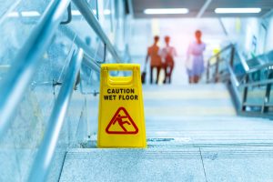 A yellow caution sign warns employees that the staircase is wet