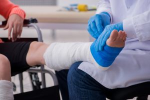 A doctor removing bandages on a person's foot in order to treat puncture wounds and avoid a tetanus infection