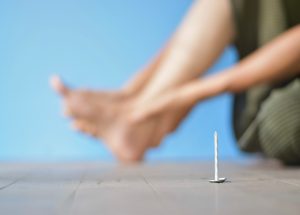 A person holding their foot after sustaining a nail puncture wound