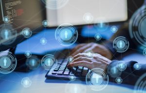 A man types on a keyboard while committing a cyber attack against a business