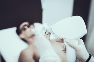 A young man undergoing a laser hair removal procedure in a salon 