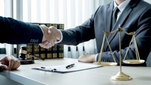 Solicitor shaking hands with client after agreeing to help them seek compensation on behalf of someone else.