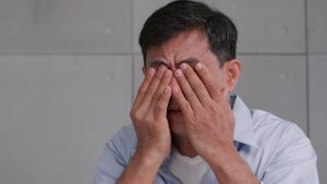 A man is rubbing his eyes after being involved in an accident at work and he's thinking of pursuing a loss of sight claim.
