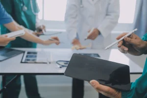 A team of doctors examining patient medical records around a table