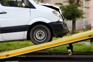 A white work van is removed from the scene of a crash.