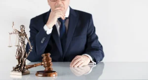 A dog bite lawyer sits behind a table with a gavel and lady justice. 