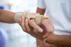 A medical professional holding a patient's injured hand that has been put in a wrist support.