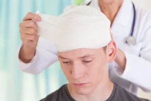 An injured person getting his head bandaged by a medical professional.