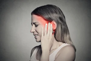A woman holding the side of her head in pain, which is highlighted by a red glow.