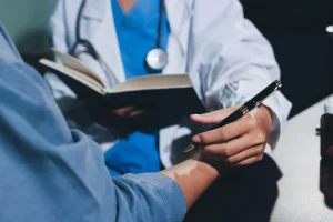 A doctor holding a book and pen while treating a patient