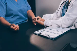 A doctor in a white medical coat provides comfort to another person