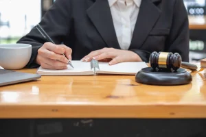 A solicitor writing notes on manual handling claims in a notebook next to a coffee cup and a gavel.