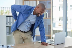 An office employee holding his back in pain.