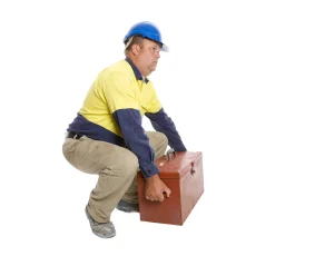 A man squatting to lift a heavy tool box. 
