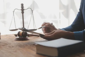 A solicitor sat at a table next to scales and a gavel reading through a clipboard detailing surgery negligence compensation.