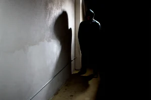 A man stands in a dark alley.