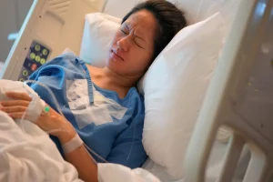 A woman in a hospital bed suffers from PTSD after a negligent birth.