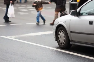 Grey car stopped for a busy pedestrian crossing. 