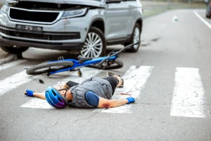 A rider lies on the ground with serious injuries after an accident involving a car.
