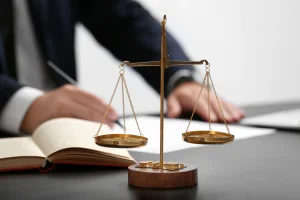 A solicitor writes notes at a table with justice scales during the motorcycle accident claims process.